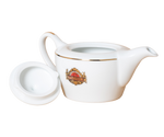 Porcelanowy imbryk z logo Basilur i złotymi zdobieniami.